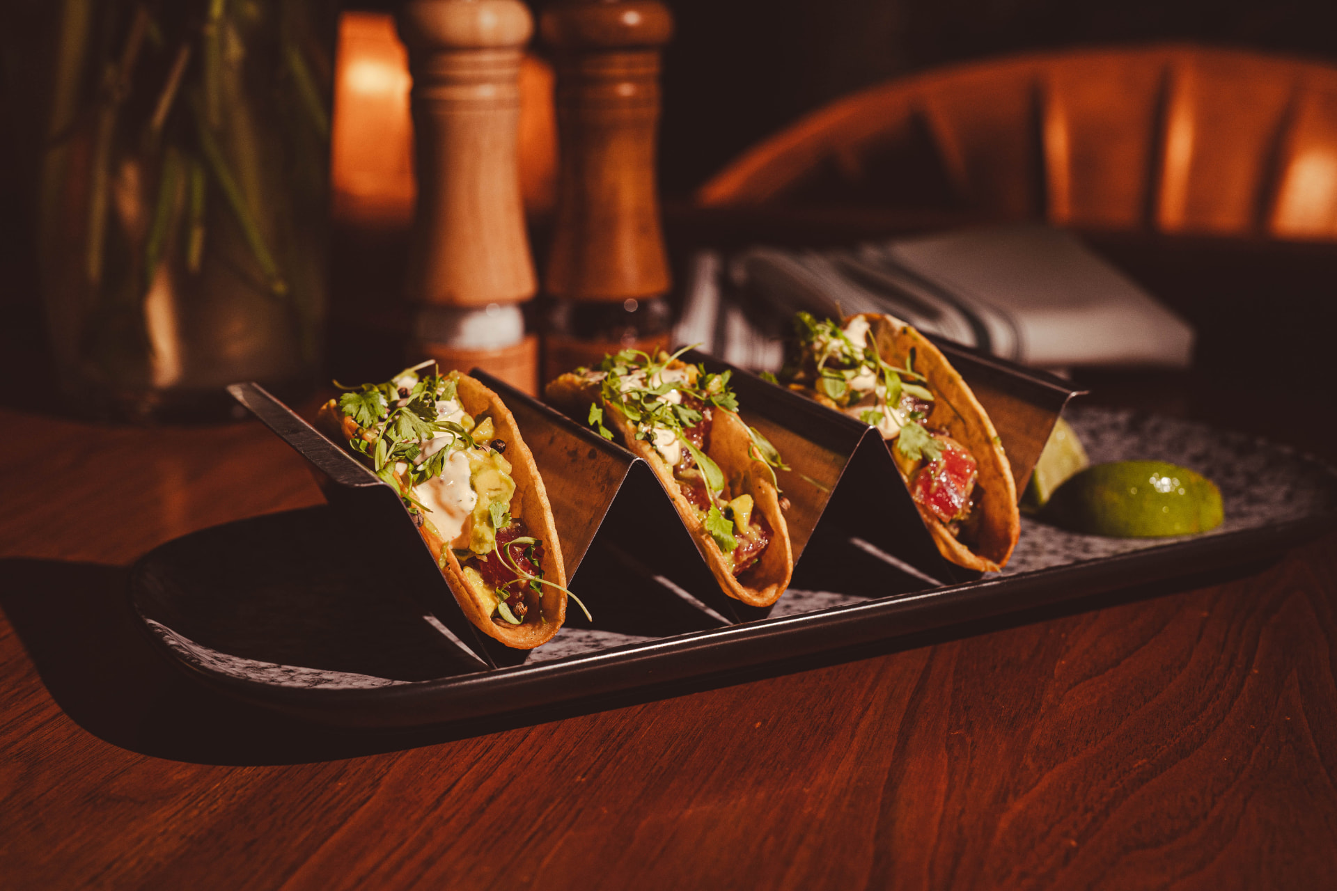 Three tacos with lime wedges