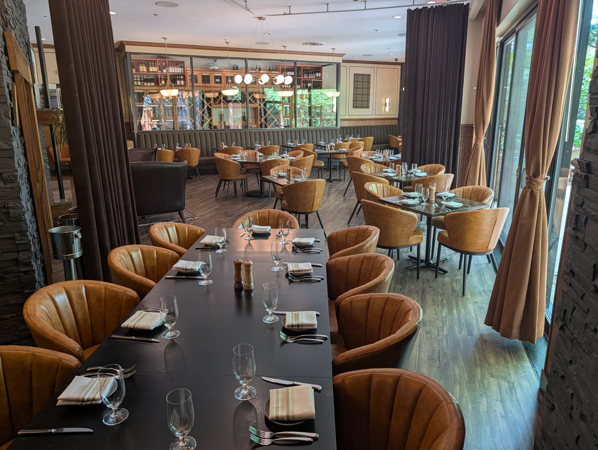 A long communal table facing a glass-enclosed wine display in the dining room