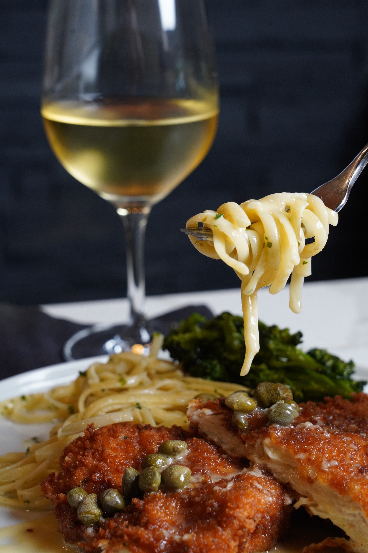 Crispy chicken Milanese with linguine and a glass of white wine