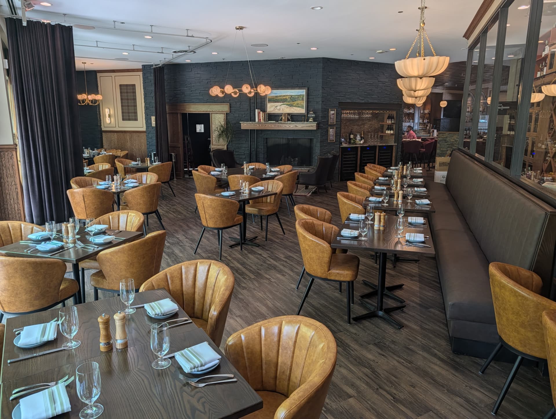 The dining room with caramel leather chairs, a banquette and a stone fireplace
